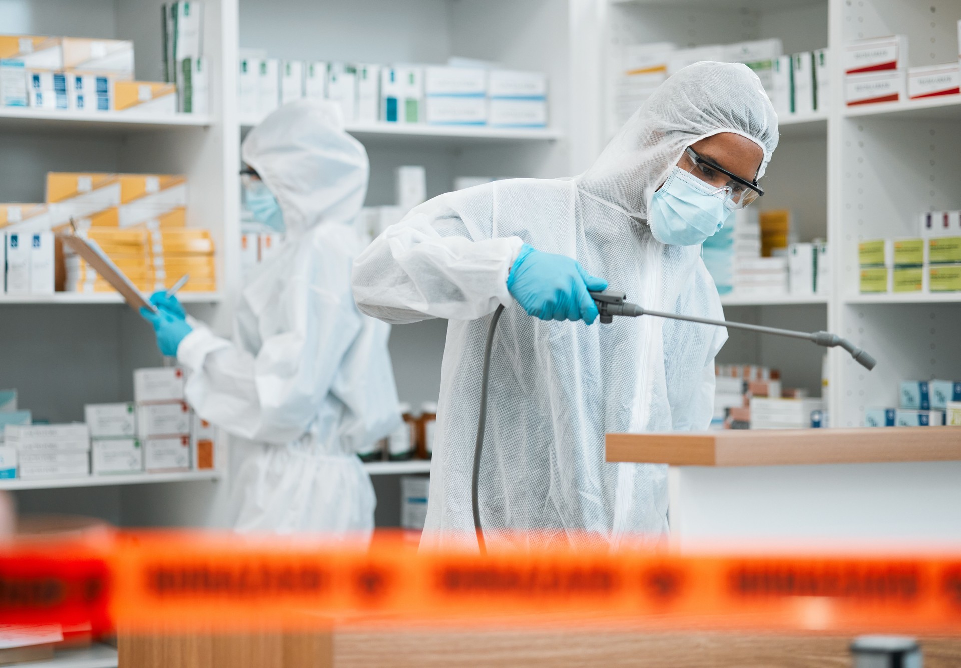 Hazmat, chemical and disinfect with people in a pharmacy for decontamination after a medical accident. Biohazard, spray or cleaning with healthcare personnel in a drugstore to sanitize and isolate